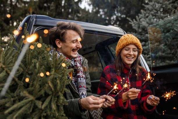 jovem casal com faíscas e nova árvore de natal - fun knit hat adult dating - fotografias e filmes do acervo