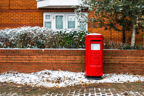 A red mailbox is mounted on a wall, with visible mail inside and slightly worn paint on the top lid.