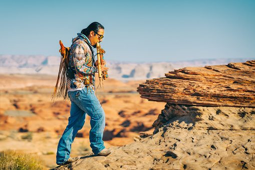 Native American flute player performing,  Glen Canyon sunrise, Arizona.  Arizona, USA- September 30, 2021