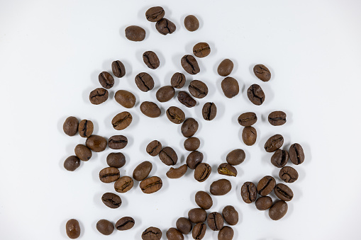 many brown coffee beans photographed from above against white background, studio shot, caffeinated soaked