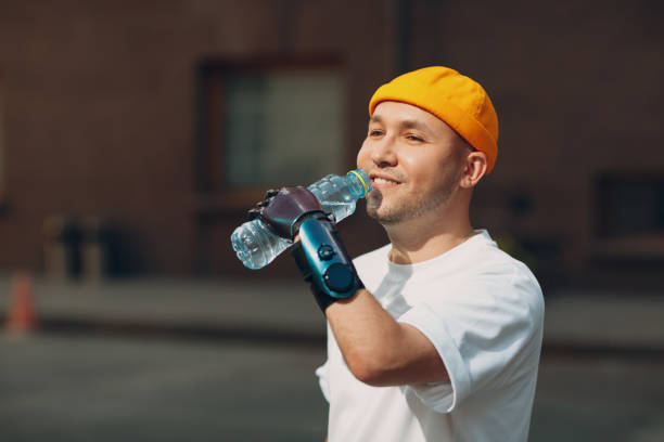 istock Young disabled man hold and drink bottled pure water with artificial prosthetic hand in casual clothes. 1357368767