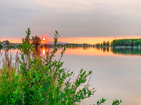 As the sun sets in Anchorage, Alaska, the colors play across the waters of Lake Hood. This lake is used as a runway for float planes.  It offers a stunning view. On this night the lake was as smooth as glass.