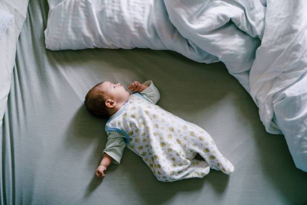 istock Baby in rompers is lying on the bed. Top view 1357370999