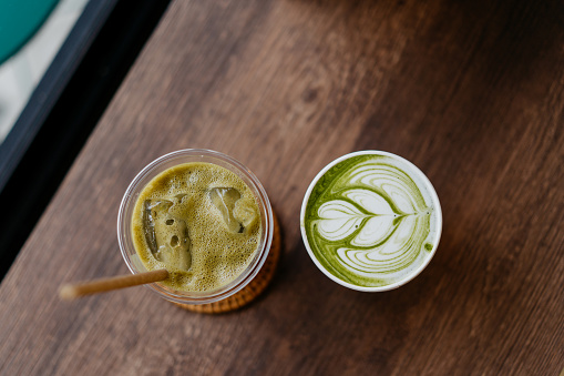 Iced Hojicha latte and matcha tea latte on top of wooden table