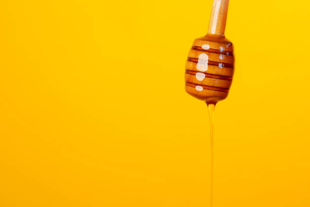 istock honey drops from a honey spoon against yellow background 1357375427