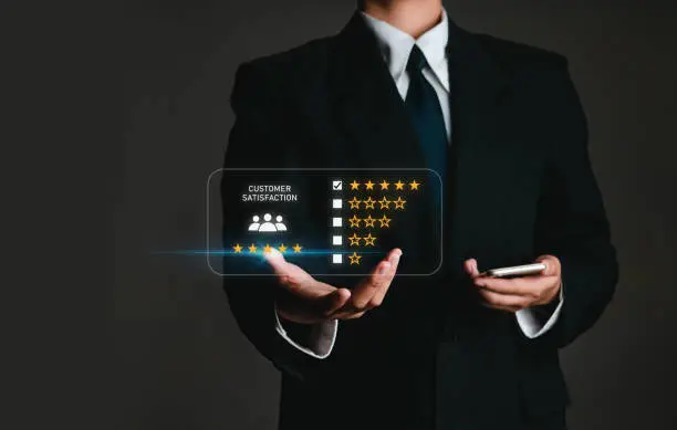 Photo of business man holding phone in customer satisfaction survey concept Users rate the service experience on the online application. Customers can assess the quality of service leading to business reputation rankings.