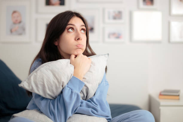 mujer estresada abrazando almohada sentada en su mal en casa - pessimist women one person caucasian fotografías e imágenes de stock