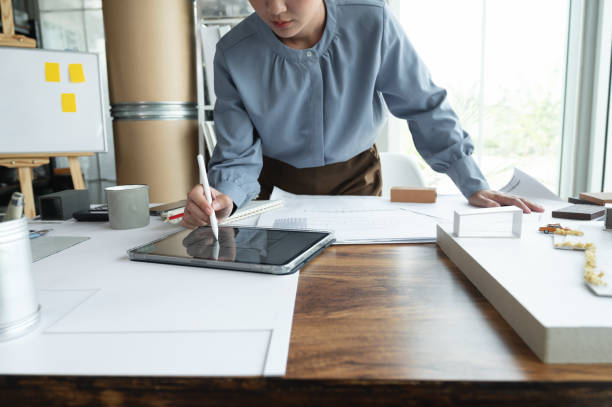 istock Female architectural designers use technology with tablets to study house plans, residential building design, home furnishing material selection, work from home support, Construction cost estimation 1357388414