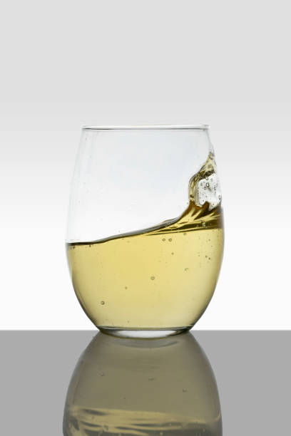verre de cristal avec des vagues de vin blanc en mouvement et un fond blanc - wineglass glass crystal studio shot photos et images de collection