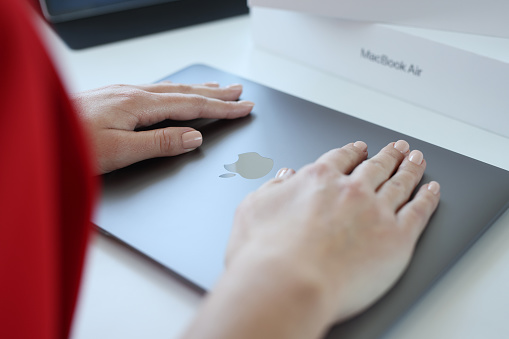 Minsk, Belarus, October 11, 2021: Woman hand rests on top cover of Apple Macbook Air. Applications for App Store in iTunes