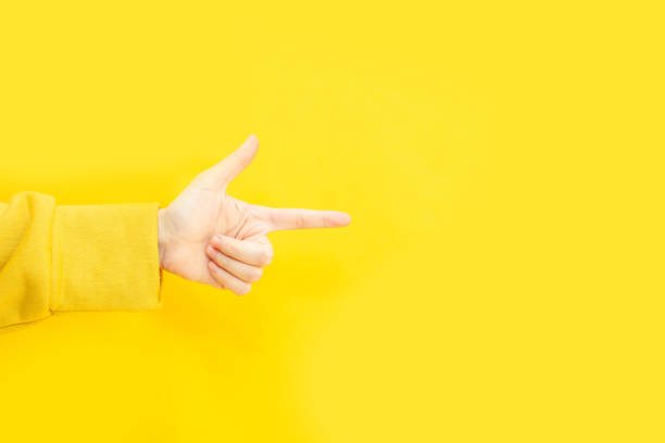 istock woman's hand make direction gesture and pointing to copy space area for advertisement promotion or text on a yellow background. 1357390168