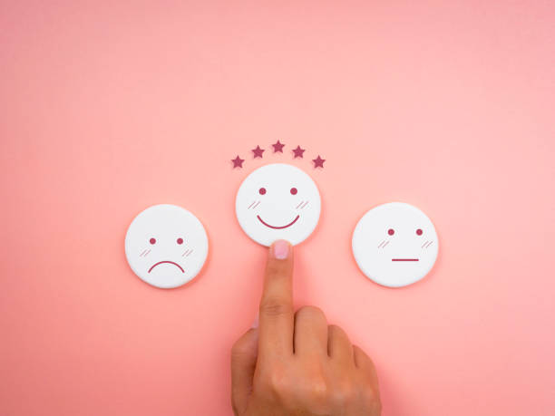 istock Customer service evaluation, ratings, feedback, client experience, and satisfaction survey concepts. Hand pointing at happy smile face on white round sponge with five stars on pink pastel background. 1357394511