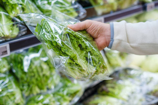 A male hand holding green lettuce leaves in a supermarket close-up stock photo