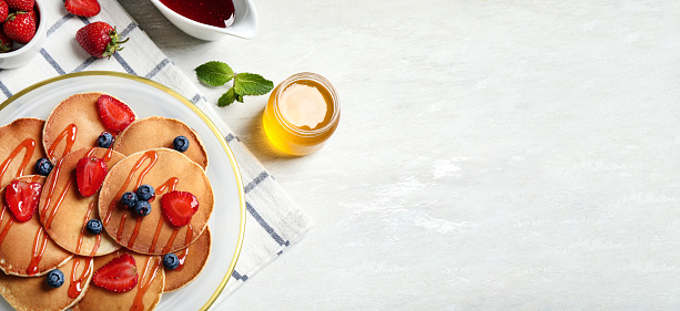 Tasty pancakes with berries served on light table, flat lay. Banner design, space for text