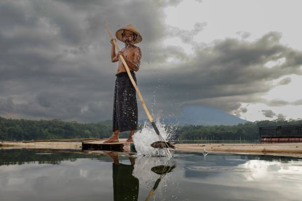 a fisherman, taking fish from the water in the lake using a spear a fisherman, taking fish from the water in the lake using a spear roe river stock pictures, royalty-free photos & images