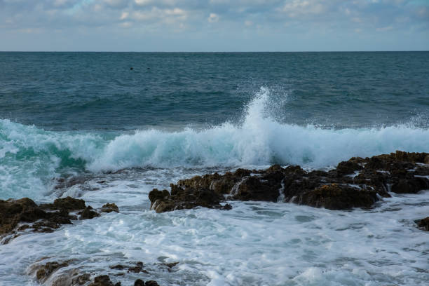 istock Turquoise sea stone beach, breaking waves on a cloudy spring day. 1357397699