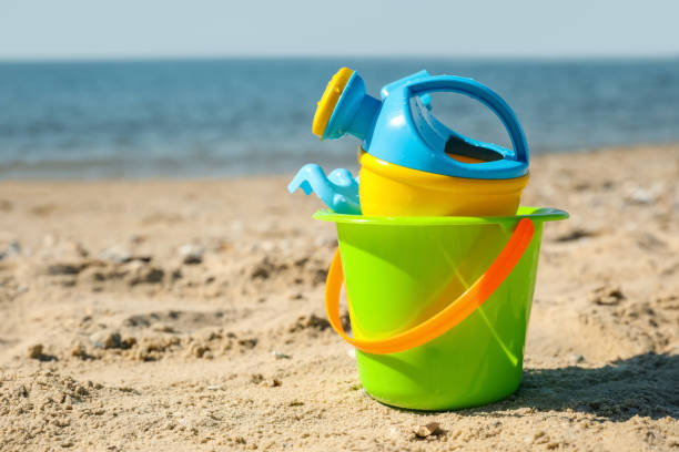 istock Different child plastic toys on sandy beach. Space for text 1357397825