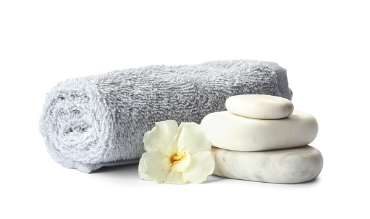 Spa stones, fresh flower and towel on white background