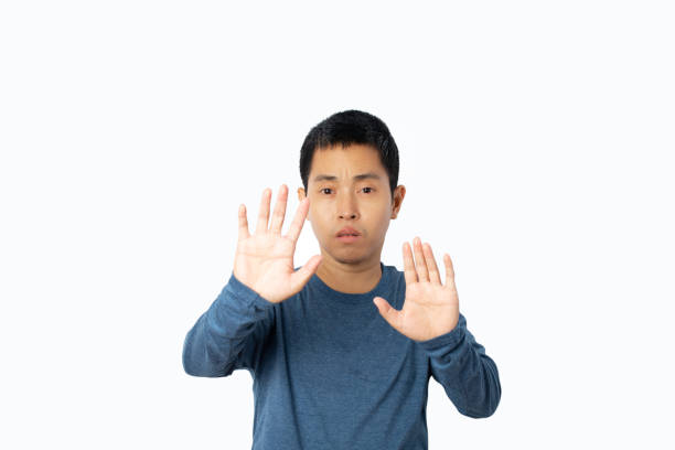 istock Young man showing stop gesture and looking scared isolated on white background. 1357402453