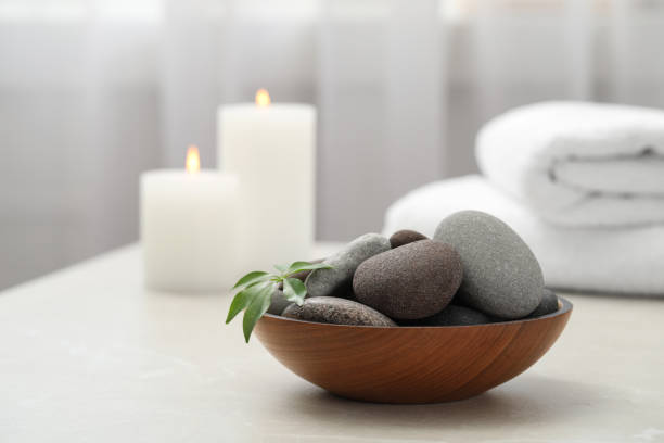 istock Spa stones in wooden bowl on white table indoors 1357404812