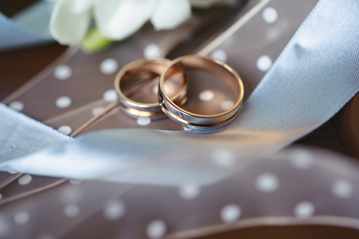 A gold ring on silk background with ribbon.