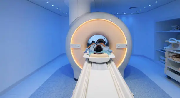 Senior male patient being slide into MRI scanner for knee scan.