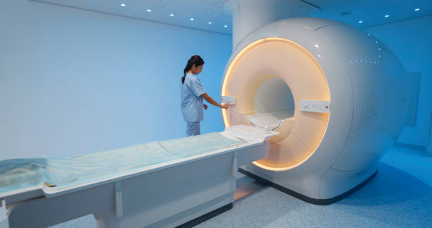 istock Female technologist standing next to MRI scanner 1357407589