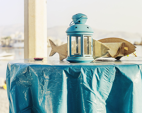 Fish shaped box and lantern candle holder placed on table by the sea - Greece