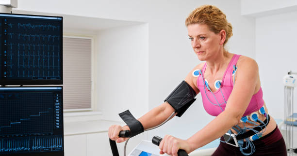 Woman taking cardiopulmonary stress test Mature woman taking cardiopulmonary exercise test by riding a bicycle ergometer in clinic. stress test stock pictures, royalty-free photos & images
