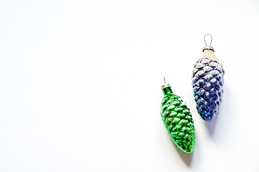 Top view of two christmas tree decorative blue and green pine cones on the white background with copy space on the left