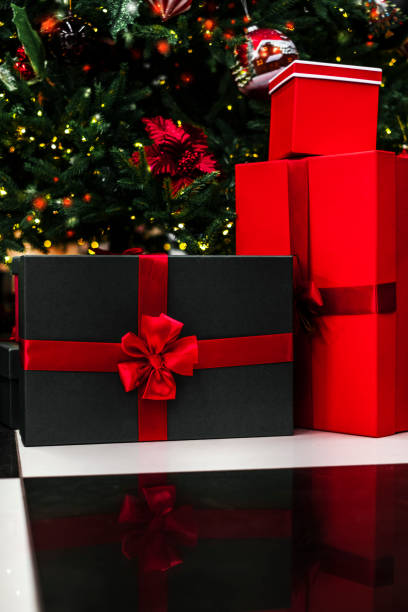 istock gift black boxes with red ribbon are beautifully packaged andlie under the Christmas tree. boxes with surprises from santa claus under the tree. christmas and happy new year 1357409447