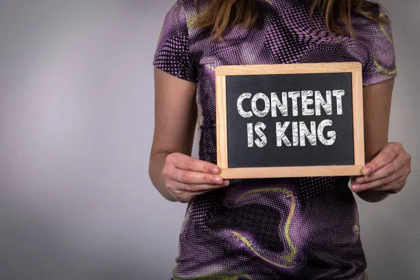 Photo of Content Is King. Woman holding a chalk board