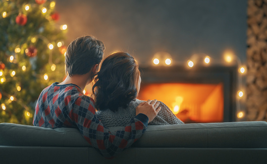 Loving couple relaxing near fireplace Christmas tree at home.
