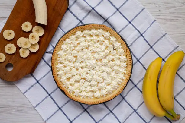 Homemade Tasty Banana Cream Pie on a white wooden surface, top view. Flat lay, overhead, from above.