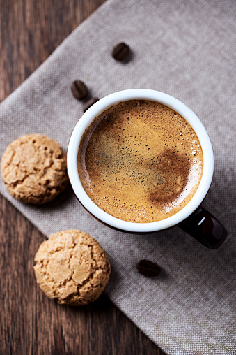 Cup of coffee with amaretti (Italian biscuits) on dark background. Top view. Close up.