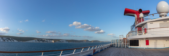 Weymouth Bay, England - July 5, 2020: Panoramic shot of open decks and red funnel on Carnival Valor. White cliffs, blue sky with white clouds in the background.