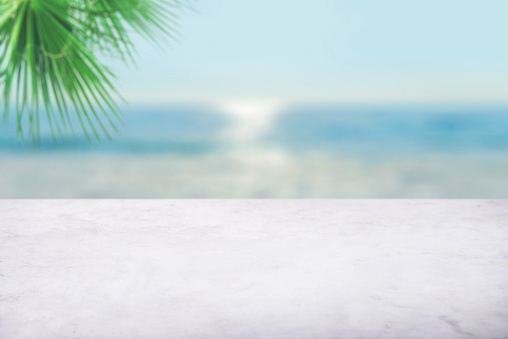 Empty white marble table top with blur sea boekh background. Mockup design for display or montage of product placement. Summer luxury layout.