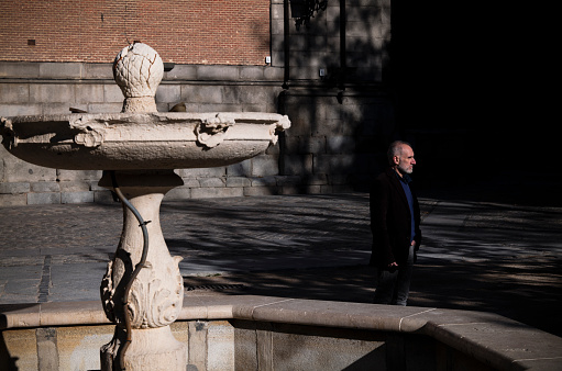 Adult man in suit standing on square with fountain. Shot in Madrid, Spain