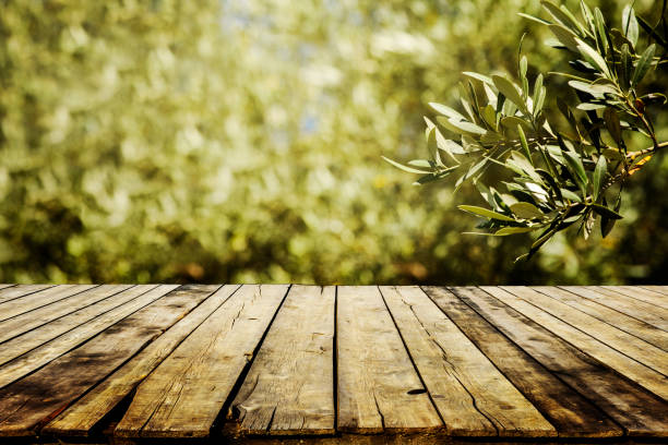 vecchio tavolo in legno per l'esposizione del prodotto con sfondo bokeh verde naturale del campo di ulivi. - oliveto foto e immagini stock