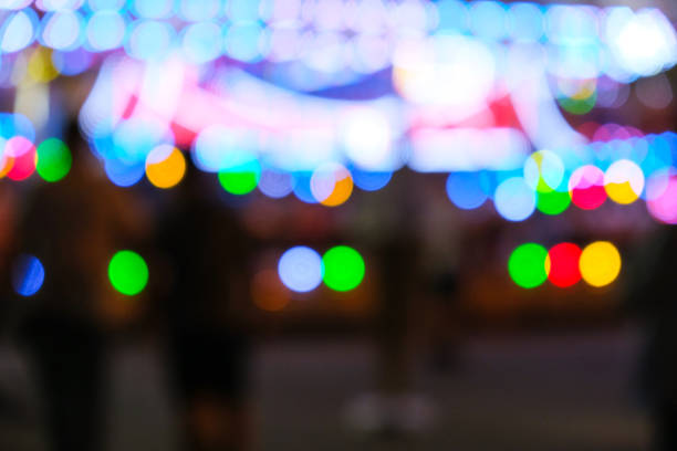 des lumières vives défocalisées clignotent lors d’un carnaval amusant la nuit. parc d’attractions bokeh lumières la nuit. divertissement de la vie nocturne - ferris wheel wheel blurred motion amusement park photos et images de collection