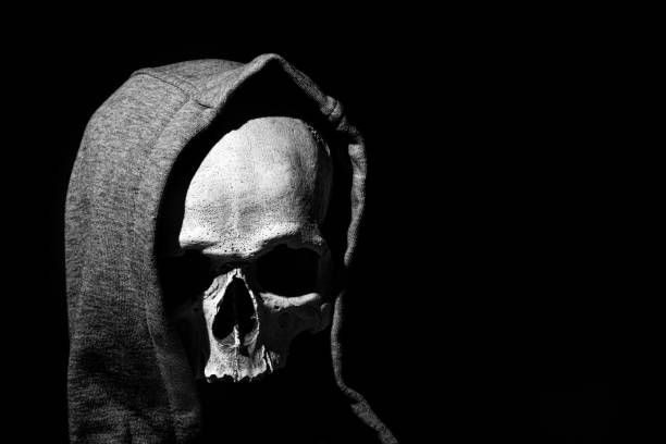 istock Human skull in hood close up on black background 1357424485