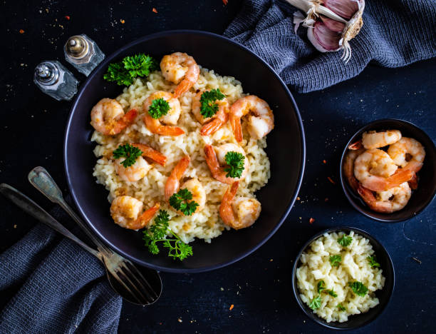 risotto con camarones sobre mesa de madera negra - arroz arborio fotografías e imágenes de stock