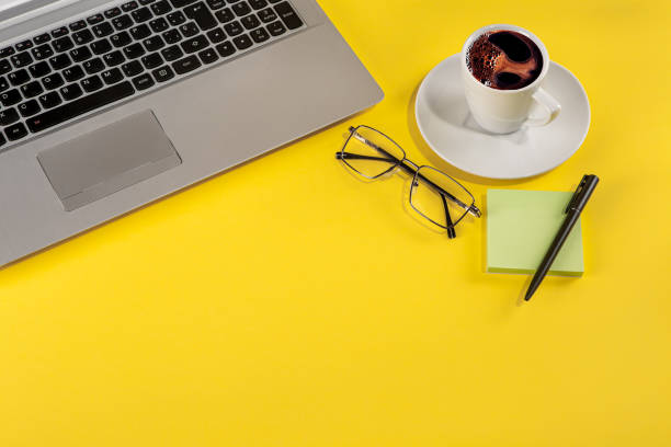 istock Still life with laptop, coffee and stationary elements on a yellow background 1357428012