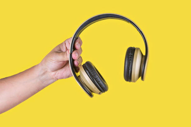 istock Person holding a brown wireless headphone in a yellow background 1357428056