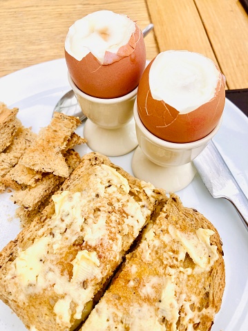 Boiled eggs in a cup with thick buttered wholemeal toast