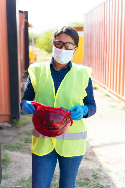 istock female construction worker with protective mask, hard hat and safety vest. 1357430131