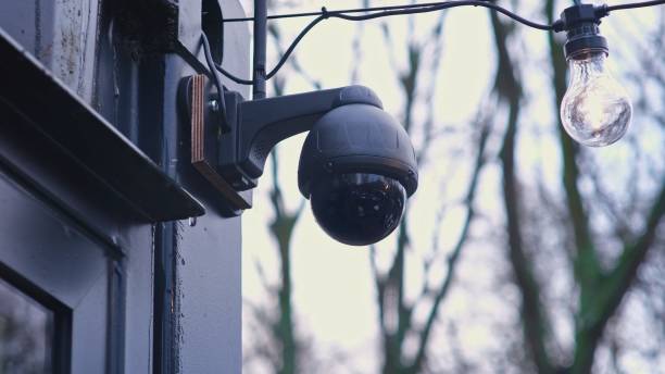 Black Surveillance CCTV Security Camera Installed on Building Corner on Rainy Autumn Day