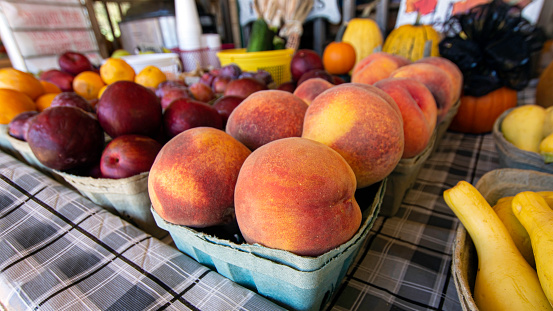 Fresh fruit and vegetables on display at a farmer's produce stand. Close up of ripe peaches.