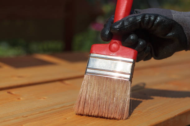 aplicación de barniz protector a tablas de madera. cepillo rojo y aceite de terraza para cubierta de madera. - wood deck wood stain paint fotografías e imágenes de stock