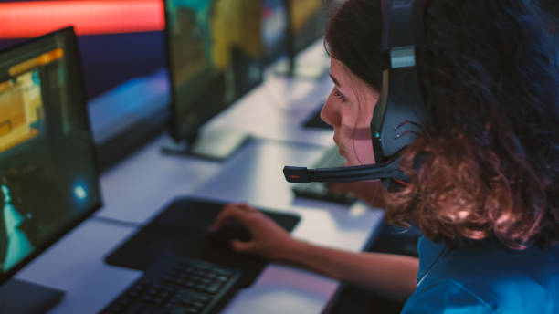 istock Pro Girl Plays Computer FPS Shooter Video Game on a Championship, Talking into Headset. Diverse Esport Team of Pro Gamers Play in Mock-up Video Game. Stylish Neon Cyber Games Arena. Over The Shoulder 1357434443